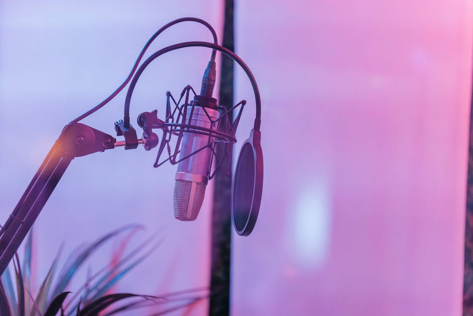 Close-up of a condenser microphone with a pop filter in a vibrant studio setting.