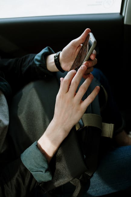A man interacts with his smartphone while seated in a car, capturing modern transportation and lifestyle.