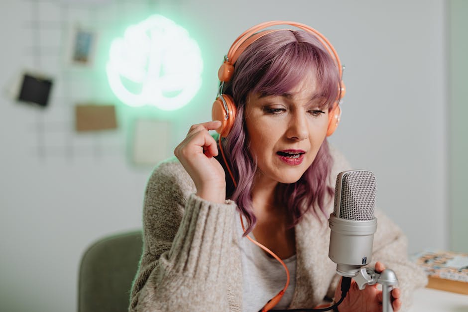 A woman recording a podcast indoors with headphones and a microphone.